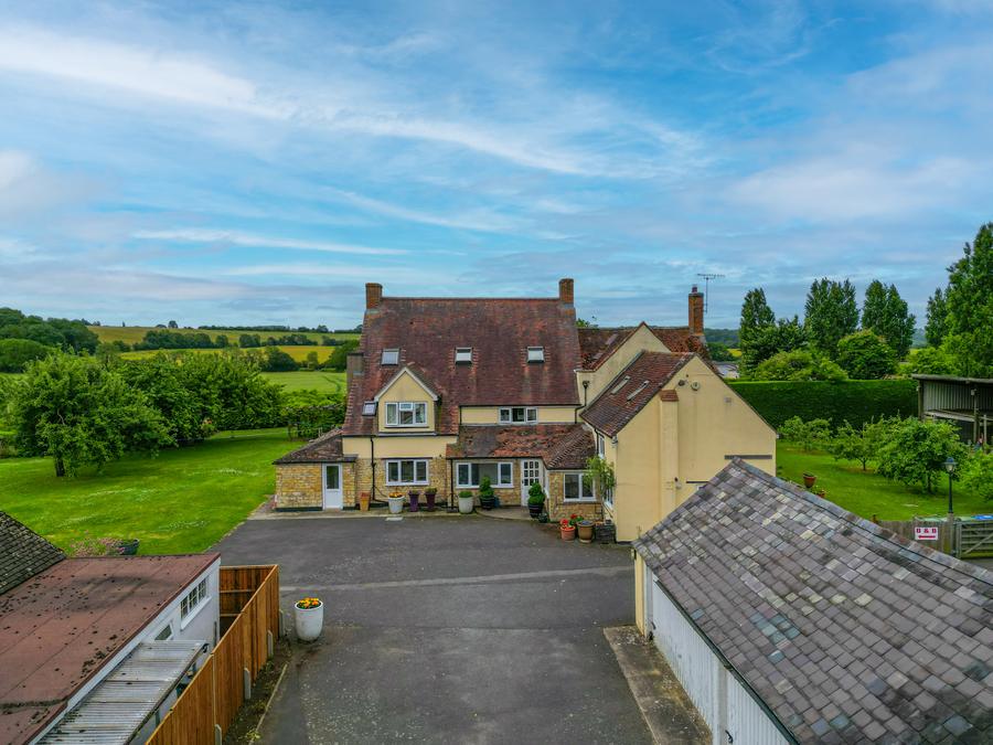 House and outbuildings around a gravel yard, open countryside beyond