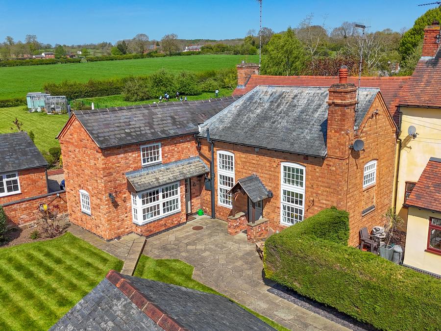 Brick farmhouse and outbuildings beside a striped lawn