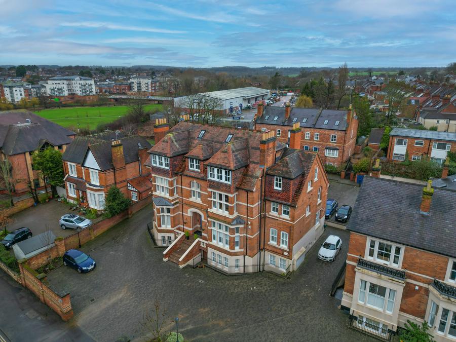 Red-brick mansion block among mature trees on the edge of a town