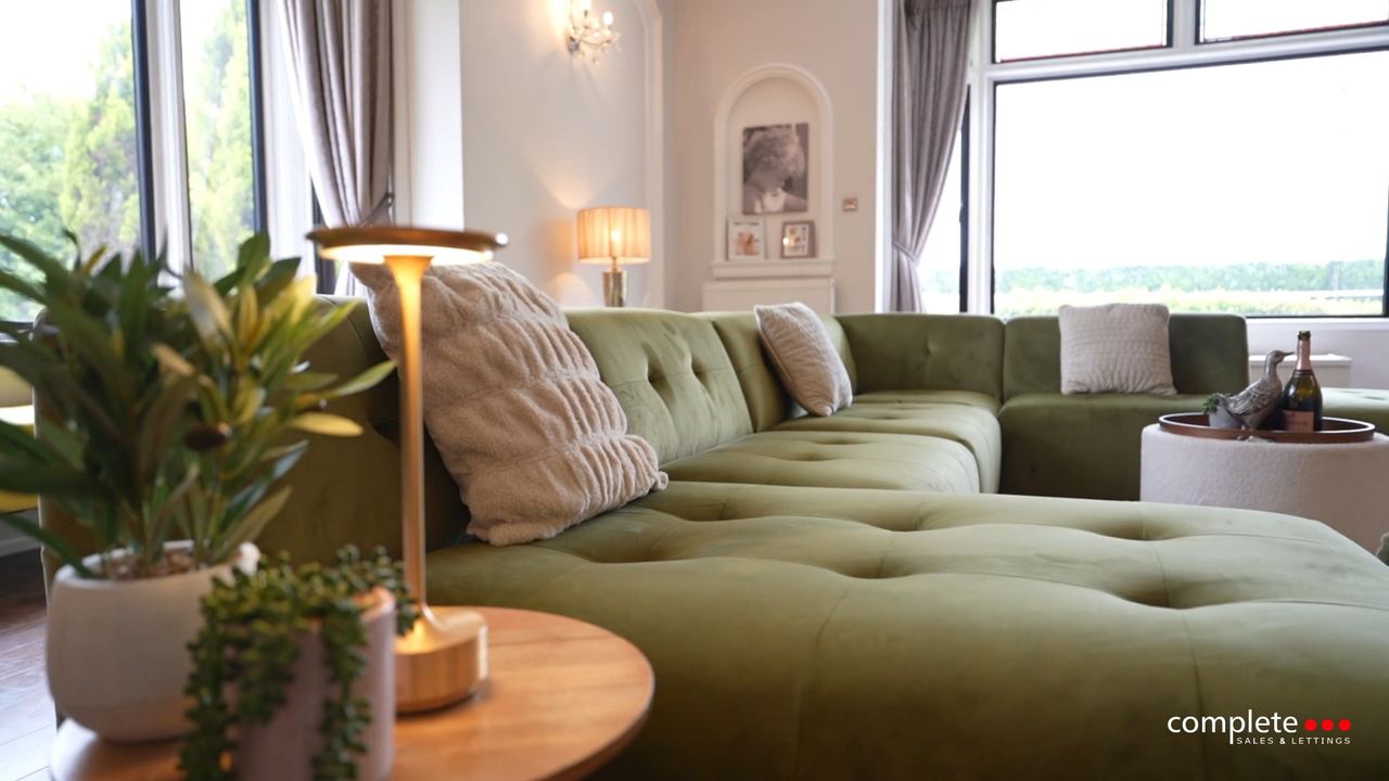 Sitting room at High Court Manor: a deep green velvet sofa below tall windows