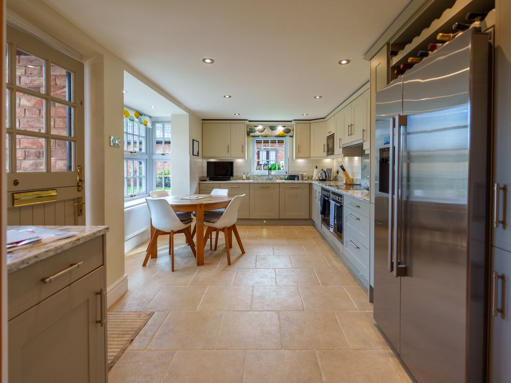 View from a hallway through to a kitchen with a dining table and tall fridge-freezer
