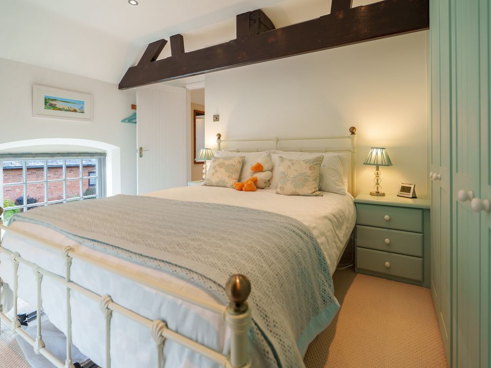 Bedroom with a cast-iron bedstead below an exposed beam