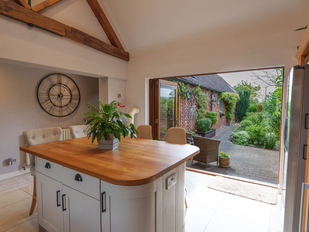 Kitchen island with an oak worktop, doors folded back to a walled courtyard