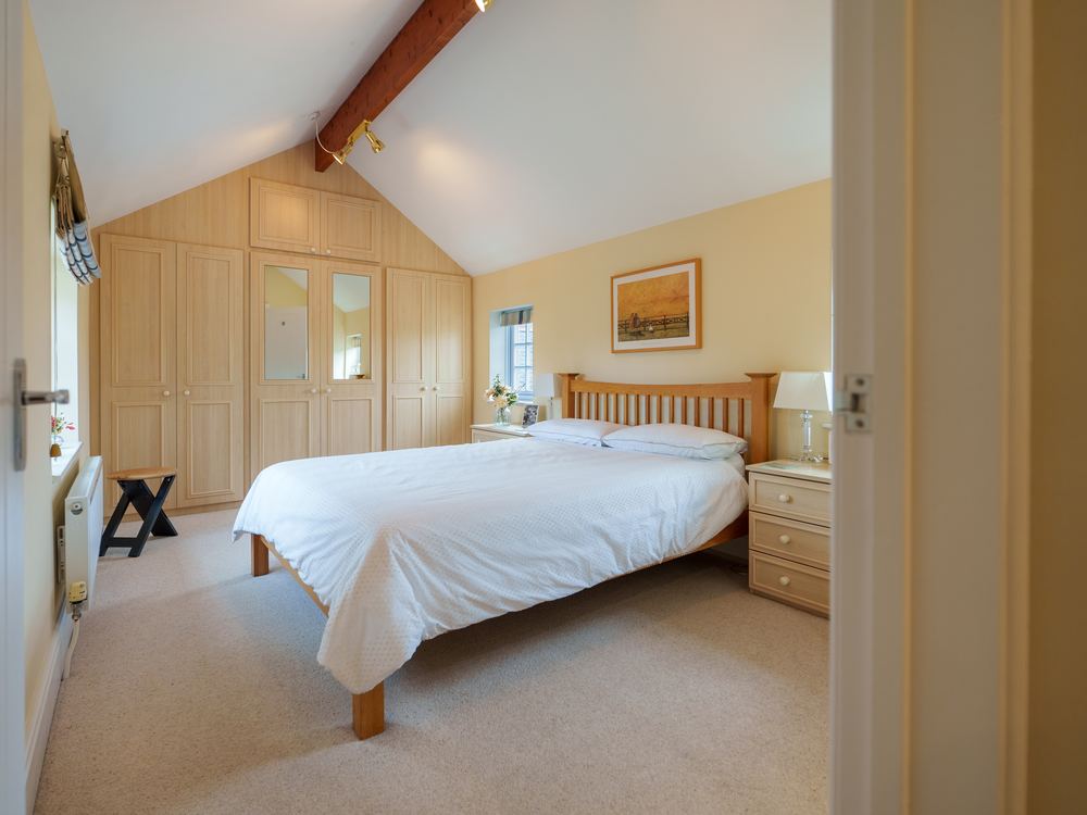 Bedroom under a vaulted ceiling with fitted wardrobes either side of the bed