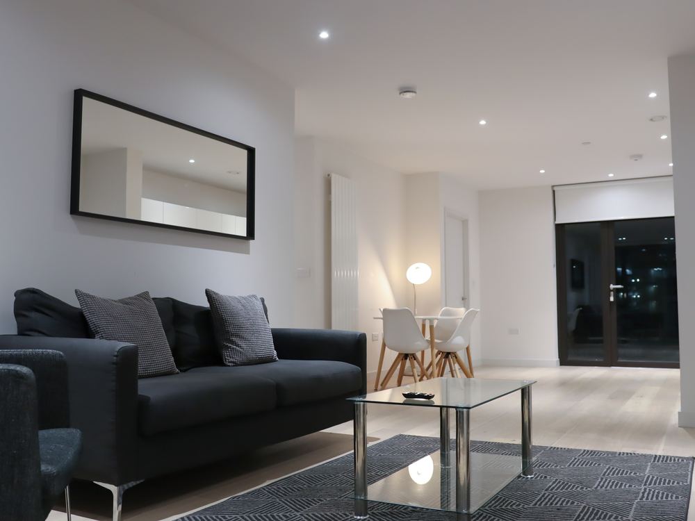 Living room in the evening, dark sofa and glass table with the dining area beyond
