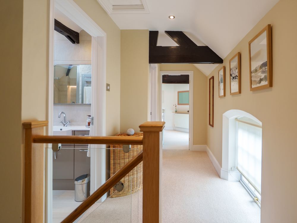 Landing with an oak banister and exposed beam, doors open to a shower room
