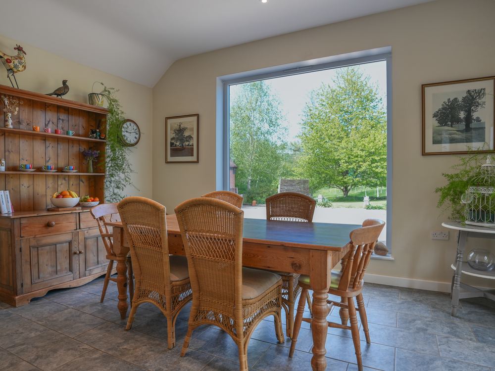 Dining room with a pine dresser and wicker chairs beside a garden window