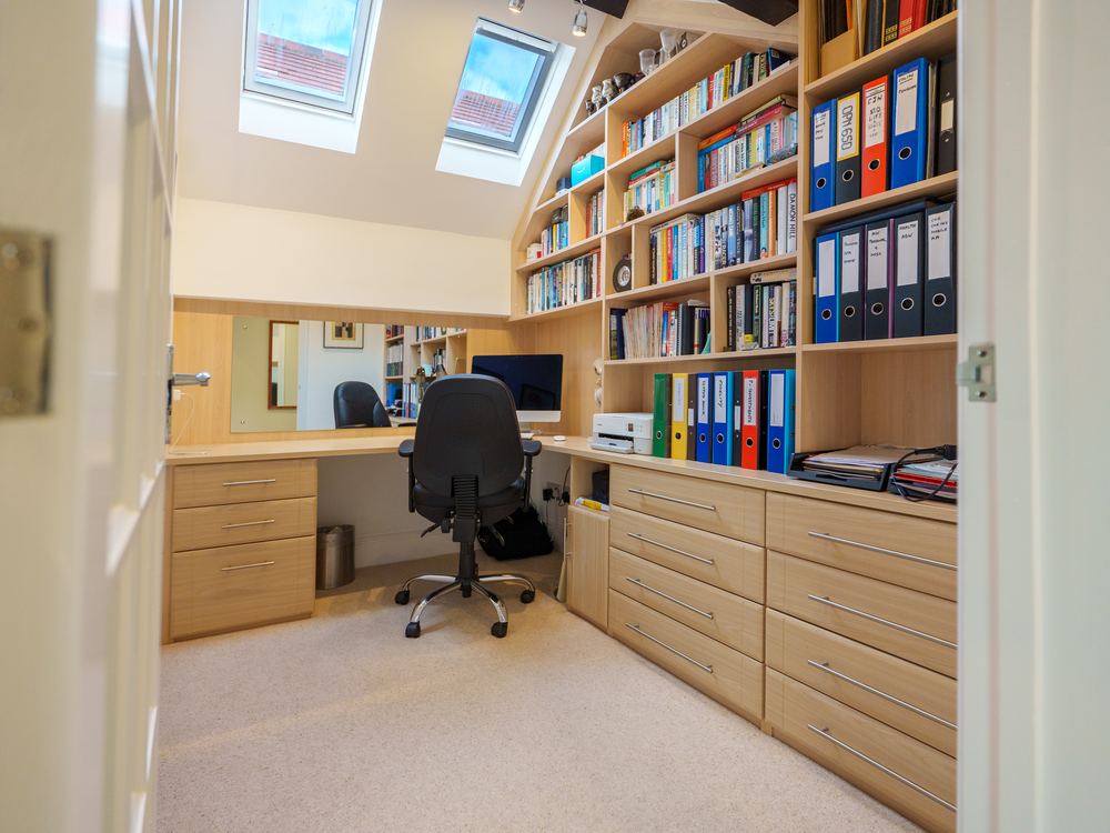 Study fitted into the eaves, with a desk and shelves of files under a rooflight