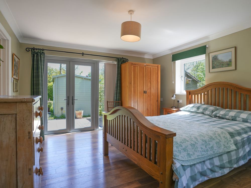 Bedroom with a wooden sleigh bed and French doors to the garden