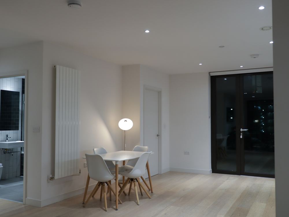 Dining area in the evening, white table and chairs beside garden doors