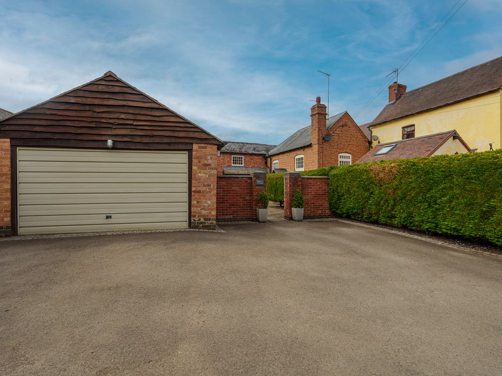 Detached double garage with a hedged driveway
